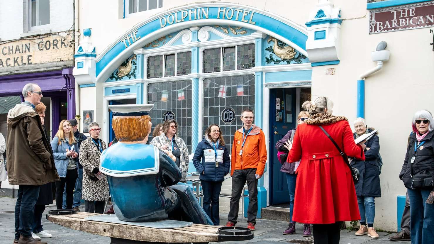 Photograph showing a group of people by a sailor statue outside the Dolphin pub in Plymouth's Barbican